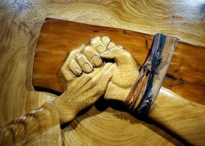 A statue of a hand holding the hand of a crucified person.