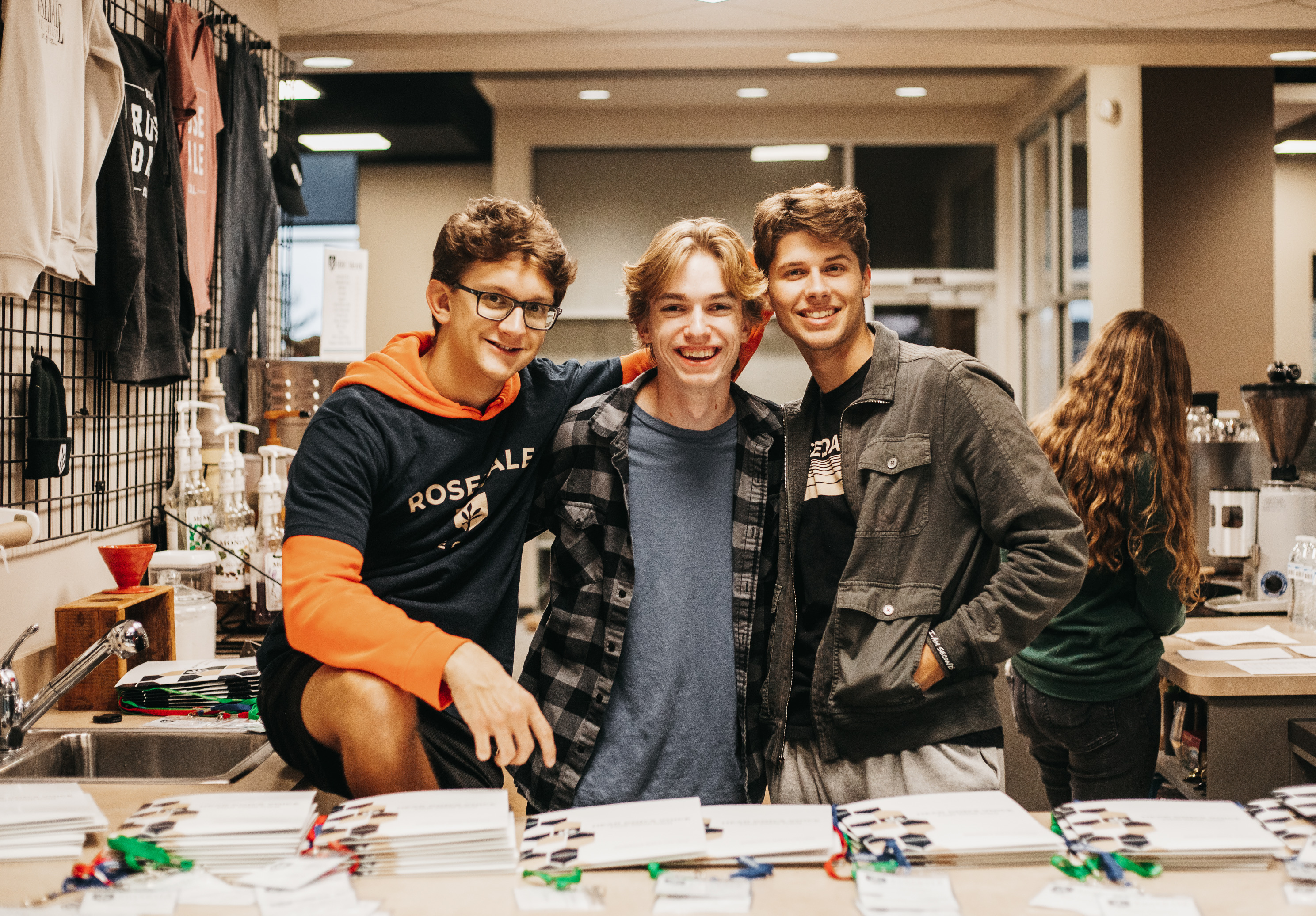 Three students pose behind a counter