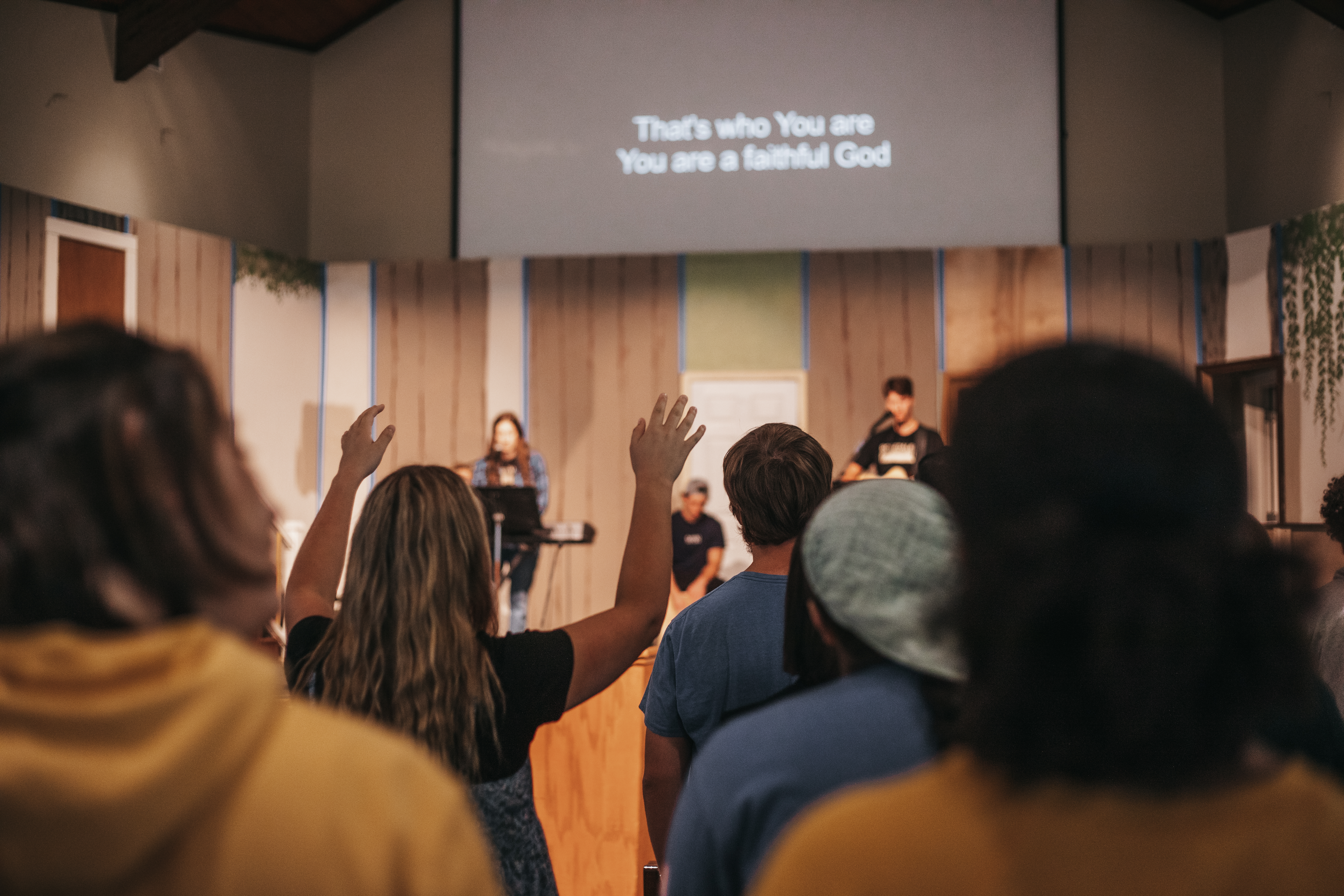 Students raise their hands while worshiping through song