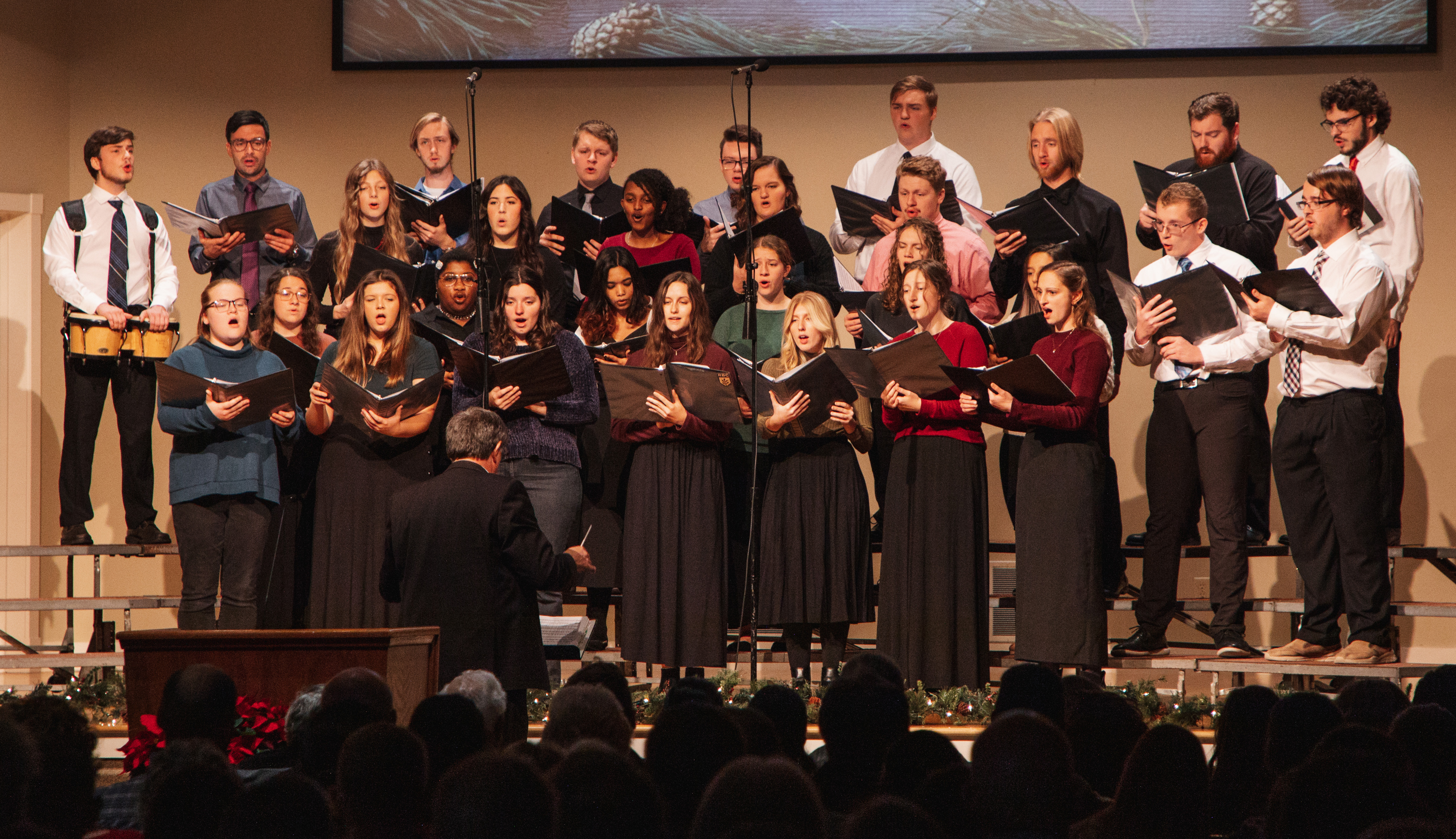 A group of students singing as a choir on a stage