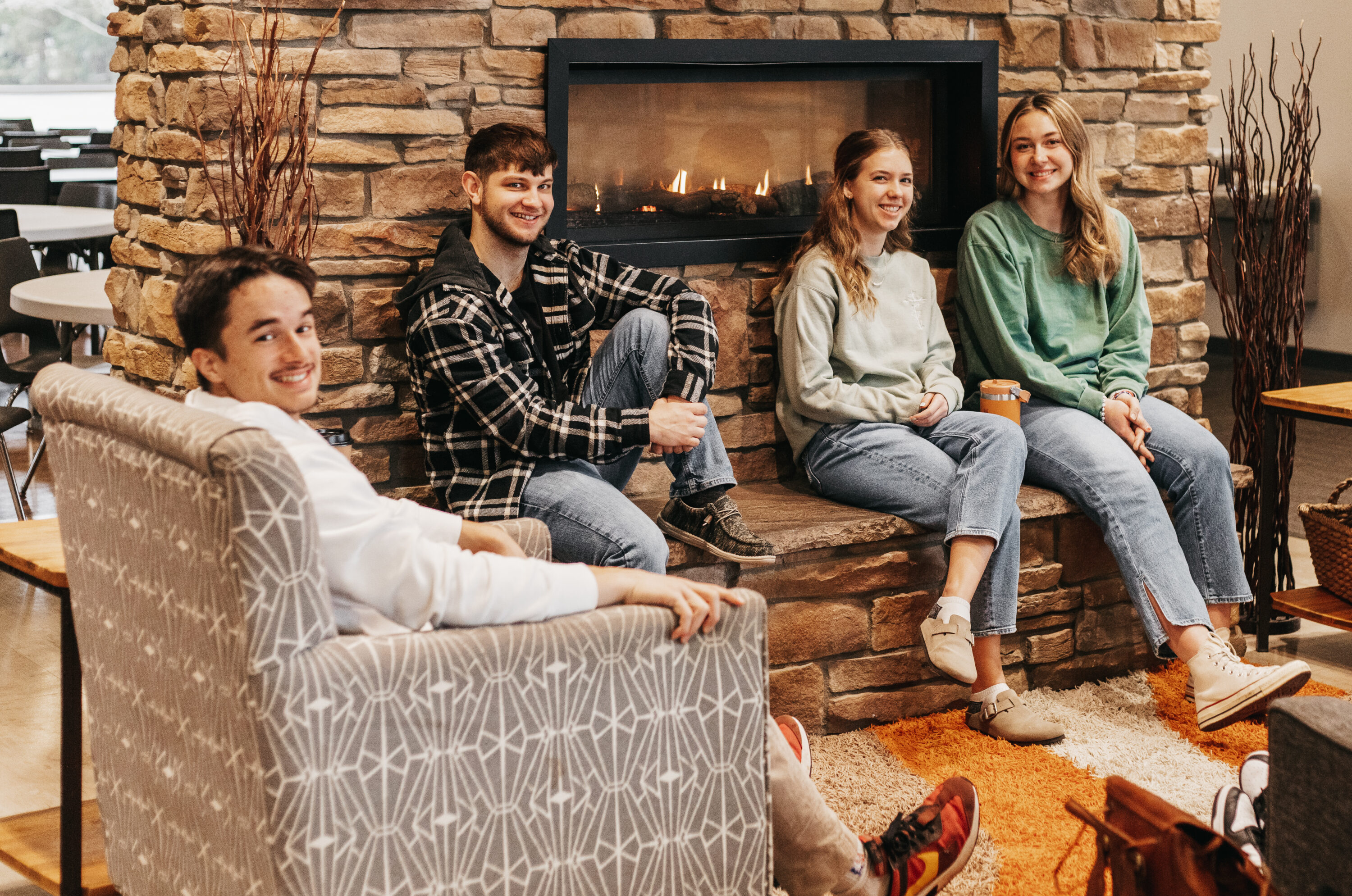 Students sitting by a fireplace.