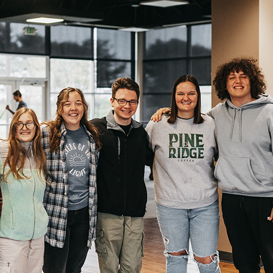 A group of students standing in a line and smiling with arms around each other's shoulders