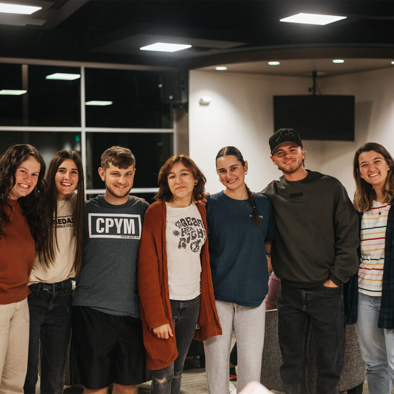 A group of students stand in a line and smile in the RBC student center