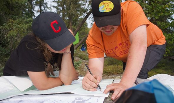 Two students looking at a map with a pencil.